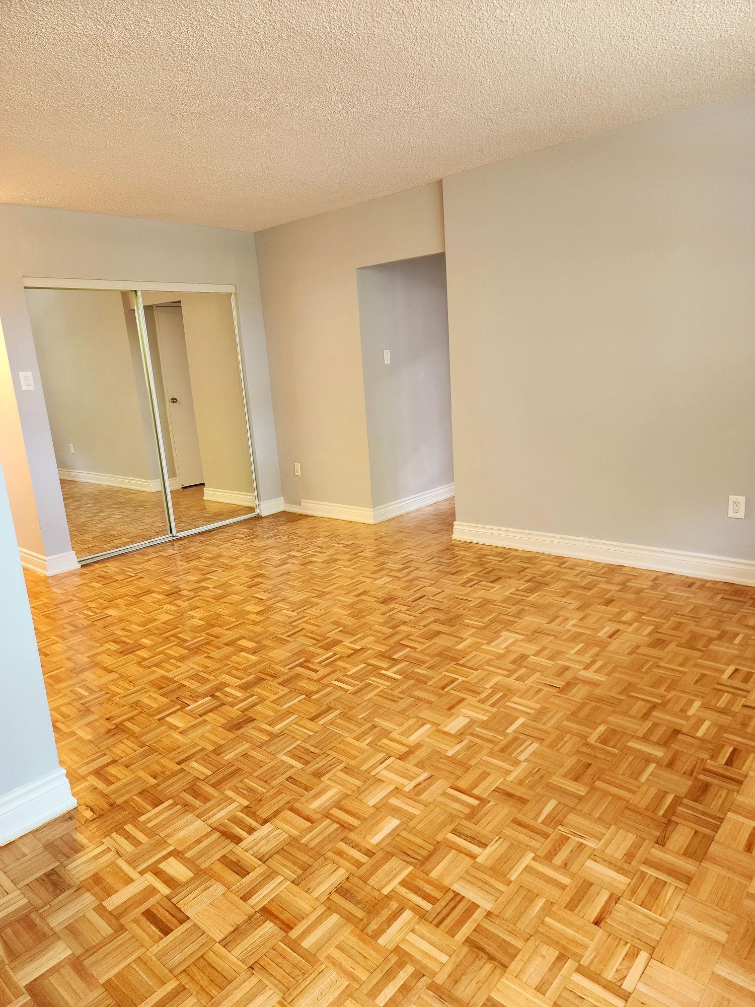 A room with wooden flooring and two doors.